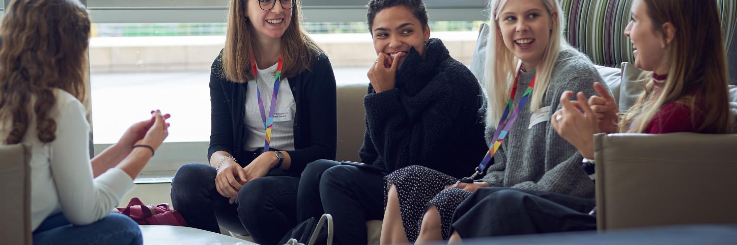 New PhD students sitting on a sofa in the Crick's atrium.