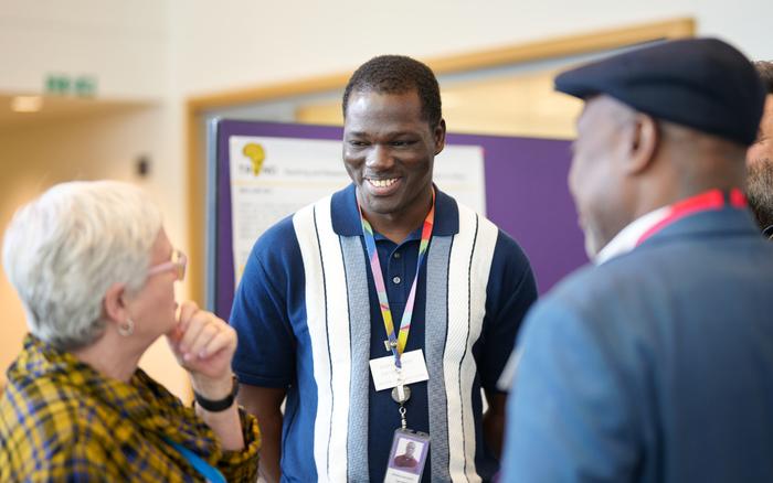 Four people talking in front of posters at the Crick Africa Network annual meeting.