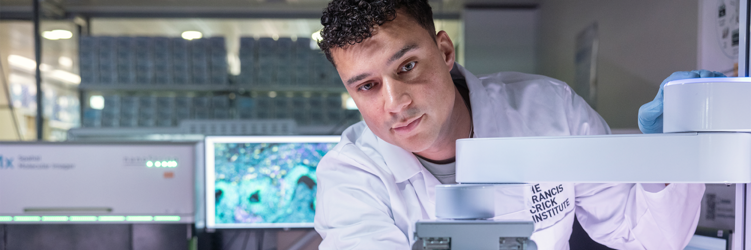 A man in a lab coat operates some scientific equipment 